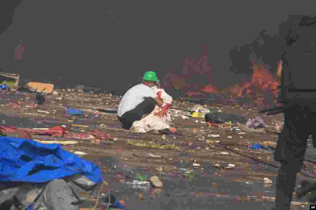 Seorang demonstran menolong korban terluka.&nbsp;(AP/Ahmed Gomaa)