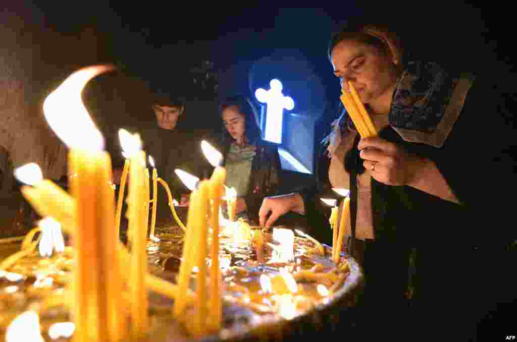 Los fieles cristianos armenios encienden velas durante un servicio religioso de Pascua en Ereván el 4 de abril de 2021.