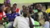 A group of youths monitor a horse race after placing a bet in Harare, Zimbabwe, Jan. 18, 2014. 