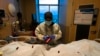 FILE - A nurse attaches a 'COVID Patient' sticker to the body bag of a patient who died of coronavirus at Providence Holy Cross Medical Center in Los Angeles, on Dec. 14, 2021.