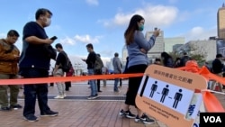 當局有指示牌呼籲排隊接受強制病毒檢測的香港市民保持社交距離。(美國之音 湯惠芸拍攝)