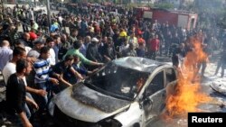 Anggota pertahanan sipil dan warga setempat berupaya memadamkan api di lokasi ledakan di pinggiran selatan Beirut (19/2). REUTERS/Issam Kobeisi