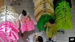 FILE - Seorang perempuan mencoba pakaian musim gugur di stan yang melakukan penjualan promosi pakaian untuk musim gugur mendatang di sebuah pusat perbelanjaan di Beijing, Minggu, 20 Agustus 2023. (AP/Andy Wong)