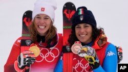 Michelle Gisin of Switzerland, gold, left, and Federica Brignone of Italy, bronze, celebrate after the medal ceremony for the women's combined at the 2022 Winter Olympics, Feb. 17, 2022, in the Yanqing district of Beijing.