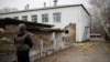 A Ukrainian soldier stands next to a damaged building housing a kindergarten after it was shelled, in the town of Stanytsia Luhanska, Luhansk region, Ukraine, Feb. 17, 2022.