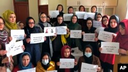 FILE -Afghan women chant and hold signs of protest, in Kabul, Afghanistan, Dec. 27, 2021.