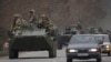 Militares ucranianos sentados encima de vehículos blindados de transporte de personal que conducen por una carretera en la región de Donetsk, en el este de Ucrania, el 24 de febrero de 2022.