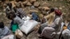 FILE - An elderly Ethiopian woman sits with others next to a sack of wheat donated to conflict victims in the town of Agula, in the Tigray region of northern Ethiopia, May 8, 2021.