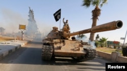 Anggota kelompok militan berdiri diatas tank ketika mengikuti parade militer di jalanan provisinsi Raqqa. (Foto: dok.)