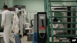  FILE - Public phones are seen near detainees in a residential pod during a media tour of the U.S. Immigration and Customs Enforcement detention center in Tacoma, Washington, Dec. 16, 2019. 