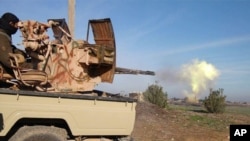In this image posted on a militant social media account by the Al-Baraka division of the Islamic State group, Feb. 24, 2015, a fighter fires a heavy weapon mounted on the back of a pickup truck in Tal Tamr, Syria.