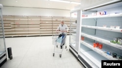 Un cliente empuja su carrito junto a los estantes vacíos en una tienda de Sainsbury's durante el brote de COVID-19, en Harpenden, Reino Unido, el 18 de marzo de 2020.
