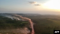 In this aerial view the red dust of the BR230 highway, known as "Transamazonica," mixes with fires at sunset in the agriculture town of Ruropolis, Para state, northern Brazil, Sept. 6, 2019.