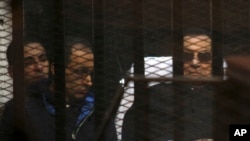 FILE - Ousted Egyptian President Hosni Mubarak, 86, next to his son Gamal, second left, in the defendants cage, during a court hearing in Cairo, Egypt.