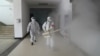 Dos voluntarios desinfectan un complejo residencial en la ciudad china de Wuhan, considerada como el epicentro del brote del coronavirus, el 22 de febrero de 2020.
