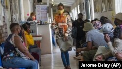 Volunteers wait to be checked at a vaccine trial facility for AstraZeneca at Soweto's Chris Sani Baragwanath Hospital outside Johannesburg, South Africa, Monday Nov. 30, 2020. (AP Photo/Jerome Delay)