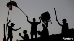 Iraqi protesters stand on concrete blast walls during an anti-government protest near a government building in Basra, Iraq, Sept. 7, 2018. 