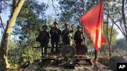 緬甸民族民主同盟軍成員在被查獲的一輛緬甸陸軍裝甲車上舉旗合影。（2023年10月28日）