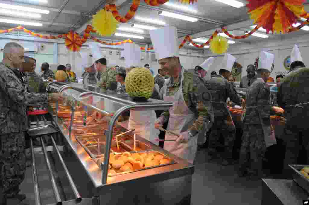 Officers of the Combined Joint Task Force – Operation Inherent Resolve, the U.S-led effort against the Islamic State group, serve their soldiers Thanksgiving Day dinner in a dining facility at Camp Arifjan, Kuwait, Nov. 23, 2017.