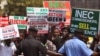 Police provide security as people demonstrate in Abuja, Nigeria, against the postponement of Nigerian elections, Feb. 7, 2015.