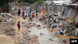 Somali people walk along a street after heavy rain storms hit the capital overnight, Mogadishu, June 8, 2018.