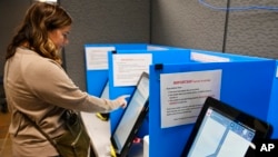 FILE-In this Nov. 5, 2019 file photo a woman votes on a new voting machine, in Dallas, Ga.