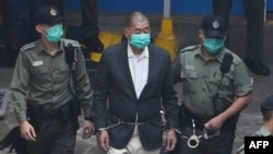(FILES) Hong Kong pro-democracy media tycoon Jimmy Lai (C) is led into a police van as he heads to court to be charged under the territory's controversial new national security law on December 12, 2020.