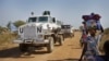 Sebuah kendaraan lapis baja PBB yang melakukan perjalanan dalam konvoi dengan truk melewati orang-orang terlantar yang berjalan menuju kamp PBB di mana mereka mencari perlindungan di Malakal, Sudan Selatan. (Foto: AP)