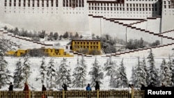 People walk past snow-covered trees outside the Potala Palace in Lhasa, Tibet Autonomous Region, China, Dec. 19, 2018. 