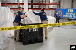 En esta imagen facilitada por el FBI, agentes asignados a un equipo especial manipulan el jueves 9 de febrero de 2023, en el laboratorio de la agencia, los materiales recuperados de un globo chino supuestamente espía que fue derribado en aguas frente a la costa de Carolina del Sur. (FBI vía AP)
