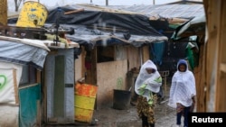 Des migrants marchent dans la boue dans la «jungle» à Calais, nord de la France, le 22 février 2016.