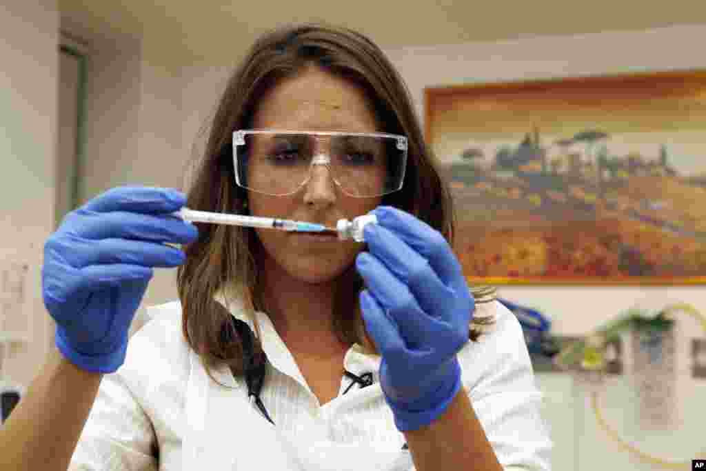 Dr Felicity Hartnell, membre de l'équipe de recherche à la clinique de l'Université d'Oxford, tient un flacon d'un vaccin expérimental contre le virus Ebola à Oxford, Angleterre mercredi 17 septembre 2014. (AP Photo / Steve Parsons / Pool)