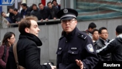 Sorang wartawan asing (kiri) ditanyai polisi di pusat kota Shanghai, China (Foto: dok).