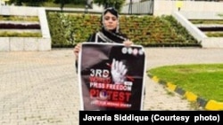 Javeria Siddique holds a banner on Press Freedom Day in Islamabad, Pakistan. Siddique says she now speaks up for everyone. "Because they all have the option to be reunited with their loved ones. I don't have that option.”