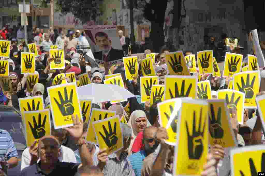 Para pengunjuk rasa mengangkat empat tangannya sebagai simbol solidaritas mereka atas 'Rabaa' - protes duduk damai - di Kairo, 23 Agustus 2013. Rabaa dalam bahasa Arab berarti empat. (H. Elrasam untuk VOA)