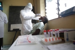 A health worker collects an oral swab from a woman during a COVID-19 coronavirus test at the Nkembo health center in Libreville, Gabon, July 9, 2020.