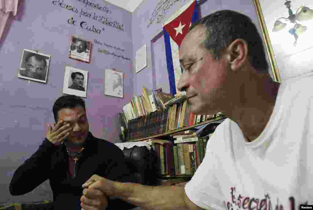 Reinier Figueredo (left) reacts while holding his father Angel's hand at their home. Angel Figueredo and his wife Haydee Gallardo (not pictured), members of the "Ladies in White" dissident group, were detained last year after shouting anti-government slogans at a rally, in Havana, Cuba, Jan. 8, 2015.