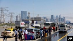 Personas esperan transporte en medio de las inundaciones causadas por las fuertes lluvias en la autopista Sheikh Zayed Road en Dubai, Emiratos Árabes Unidos, el jueves 18 de abril de 2024.