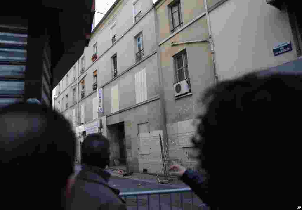 Residents watch the building of last Wednesday's raid in Saint-Denis, outside Paris.