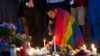 An unidentified man, wrapped in a rainbow flag, lights a candle during a vigil in Washington, June 13, 2016.