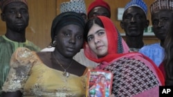 Pakistani activist Malala Yousafzai who survived being shot by the Taliban because she advocated education for girls, holds a picture of kidnapped schoolgirl Sarah Samuel with her mother Rebecca Samuel, during a visit to Abuja, Nigeria, July 13, 2014. 