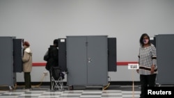 An early voter wearing a protective face mask waits to cast her vote in two runoff elections that will determine control of the U.S. Senate, in Atlanta, Dec. 4, 2020. 