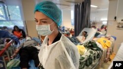 Seorang anggota staf medis berjalan di ruang isolasi COVID-19 yang ramai di Rumah Sakit Darurat Universitas di Bucharest, Rumania, 22 Oktober 2021. (Foto: AP)