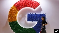 Una mujer pasa frente al logotipo de Google en la Exposición Internacional de Importaciones de China, en Shanghái, el 5 de noviembre de 2018. 