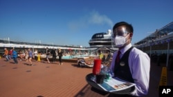FILE - A waiter, wearing a mask for COVID-19 protection, holds a tray of drinks on the MSC Grandiosa cruise ship in Civitavecchia, near Rome, March 31, 2021.