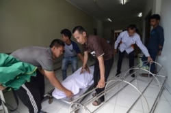 In this Monday, April 9, 2018, photo, family move the body of a victim who died from drinking poisonous bootleg liquor at a hospital in Cicalengka, West Java, Indonesia.