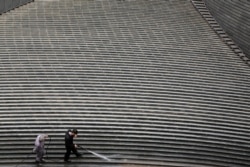 Workers clean steps near a recently erected office high-rise in Beijing, China, April 20, 2017.