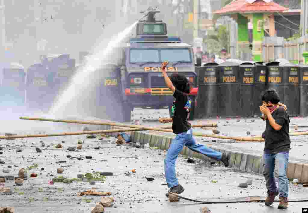 Dua mahasiswa bereaksi setelah polisi menggunakan meriam air untuk membubarkan demonstrasi anti-korupsi di di Makassar, Sulawesi Selatan yang berakhir rusuh.