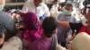 Pedagang pasar dan kuli gendong mengantri untuk mendapatkan hand sanitizer gratis dari komunitas warga Tionghoa di pasar tradisional Solo, 21 Maret 2020. (Foto: VOA/ Yudha Satriawan)