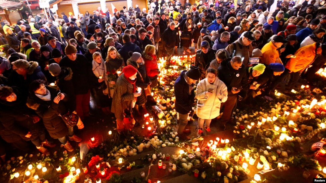 People hold candles at the memorial site of last year's truck attack in a Christmas market, which killed 12 people and injured many others, at Breitscheidplatz square in Berlin, Dec. 19, 2017. 